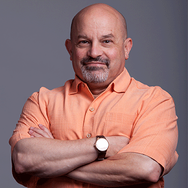 Image of Dr. Jonathan Arenberg. Arenber is standing with his arms crossed over his chest. He has a closed smile, has no hair, and wears a watch and a orange button-down. 